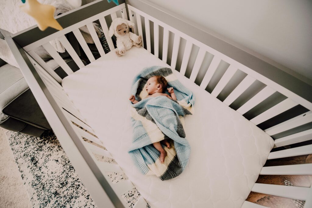 Baby ligt wakker in bed in doek